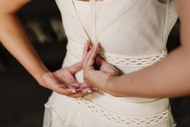 Dettaglio mani della sposa durante la chiusura dell'abito