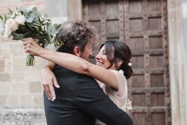 Abbraccio degli sposi con sguardo e sorrisi dopo l'uscita dalla chiesa