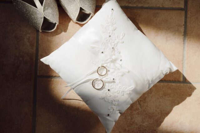 Dettaglio delle scarpe sposa con cuscinetto e fedi nuziali